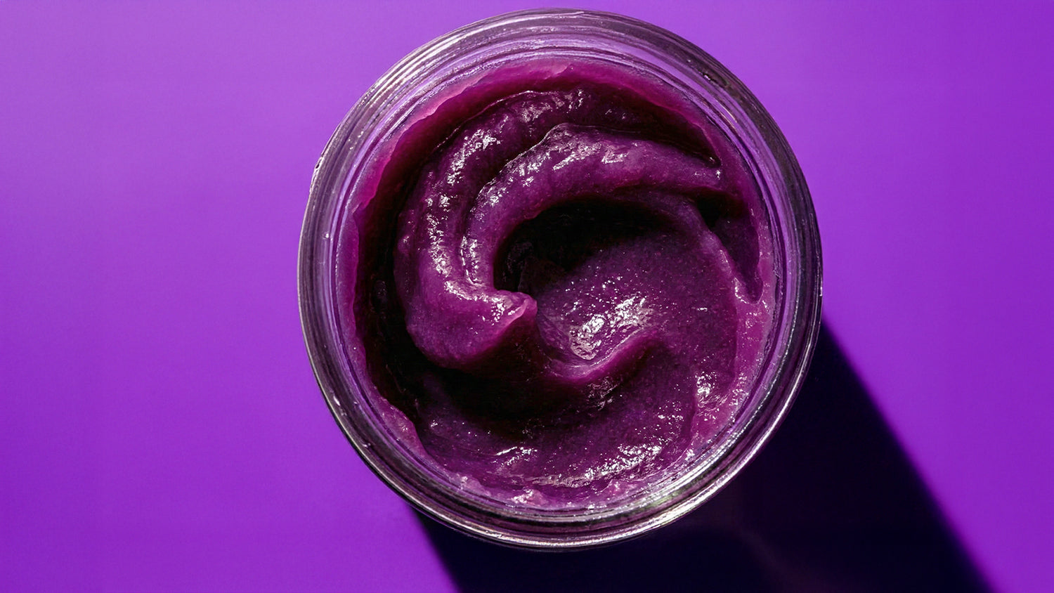 Blueberry Mossology Sea Moss Gel in a glass jar on a purple background